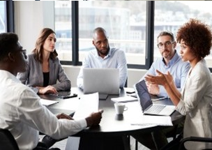 A group of people sitting around a table with laptops.