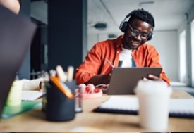 A man wearing headphones and using a laptop.