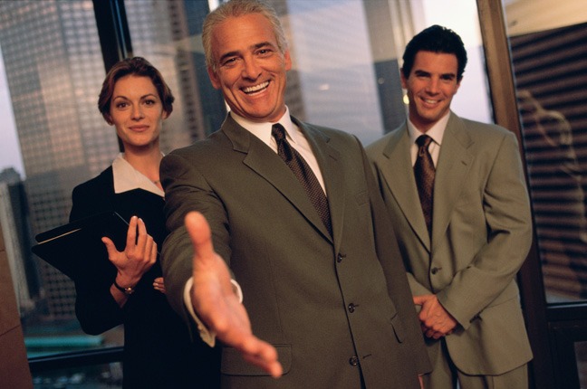 A man in a suit and tie holding out his hand.