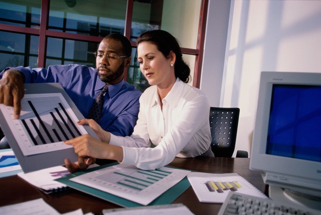 A man and woman working on papers at a desk.