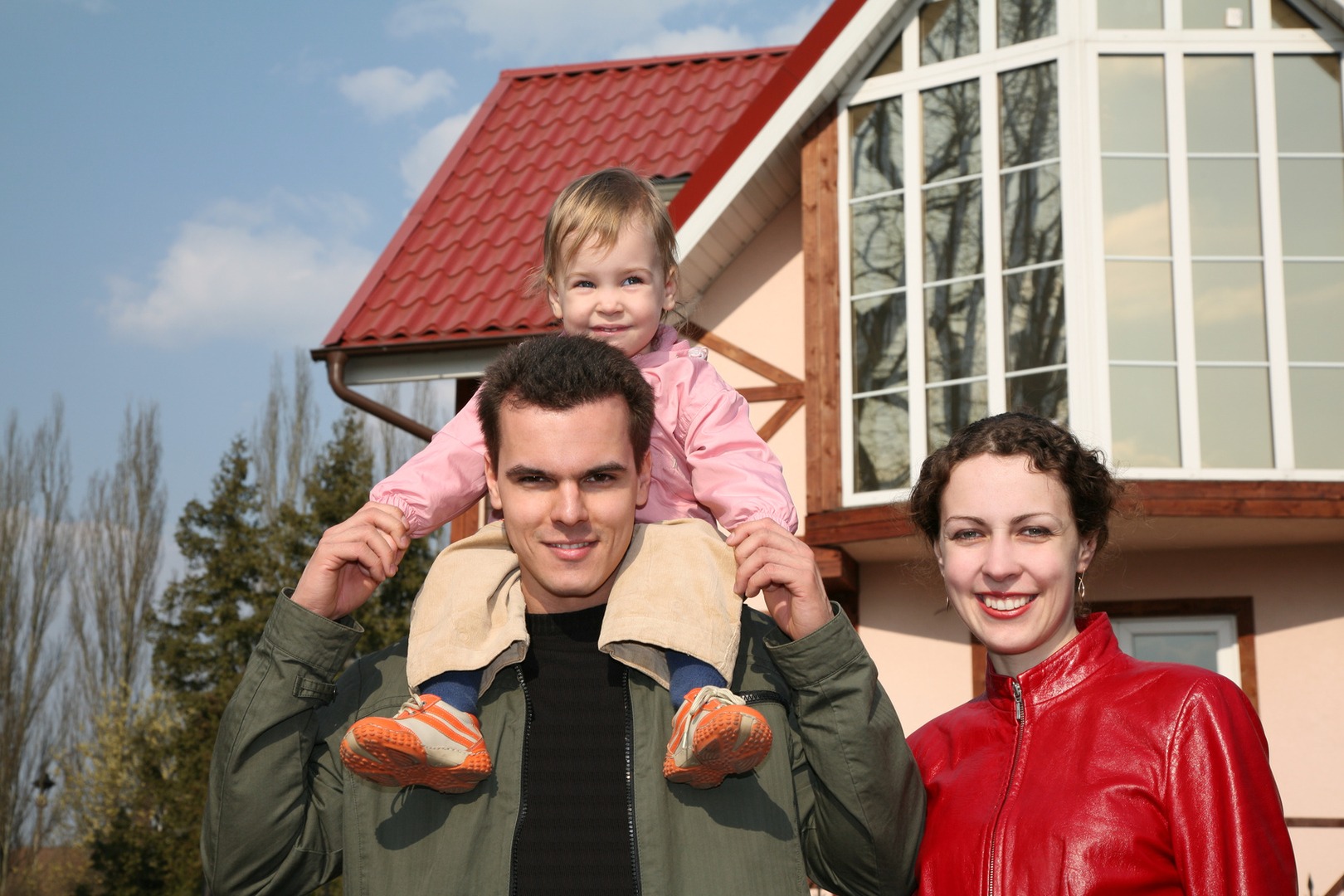 A man and woman holding a child on his shoulders.