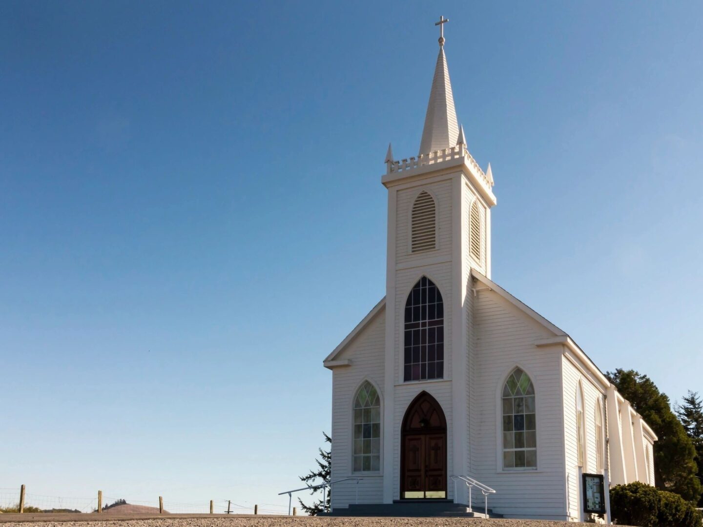 A white church with a steeple and a large clock.