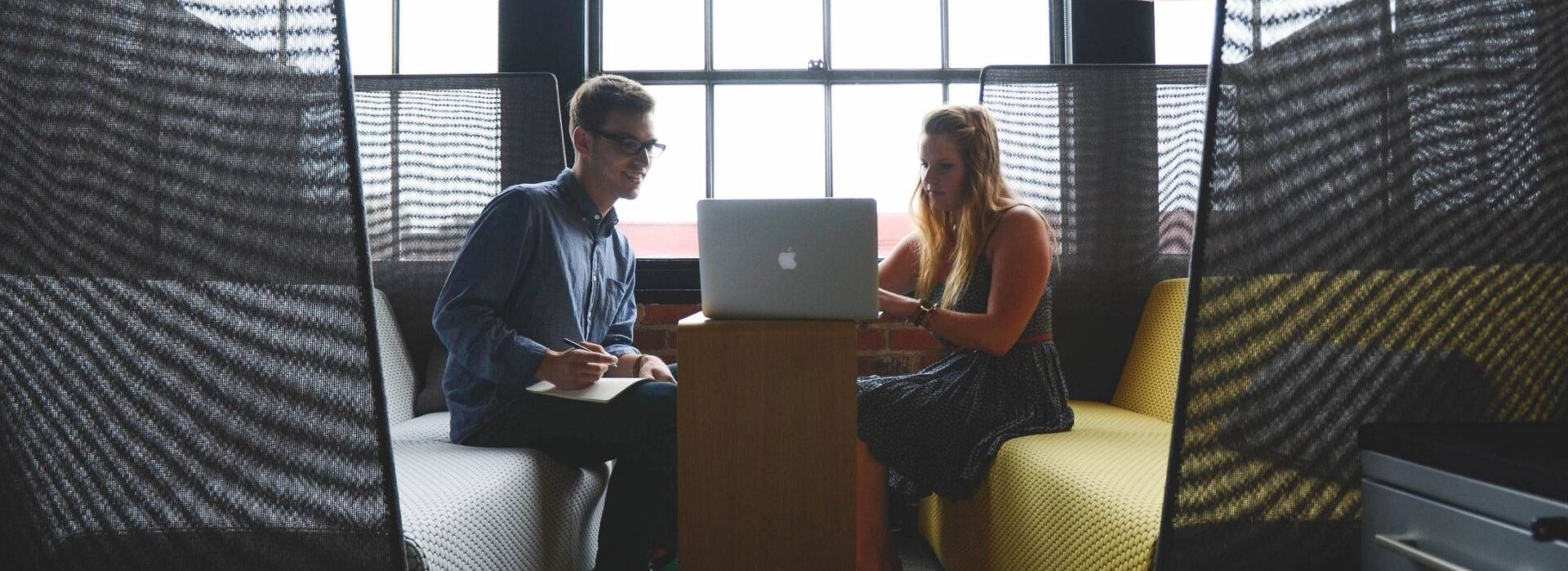 Two people sitting at a table with an open laptop.