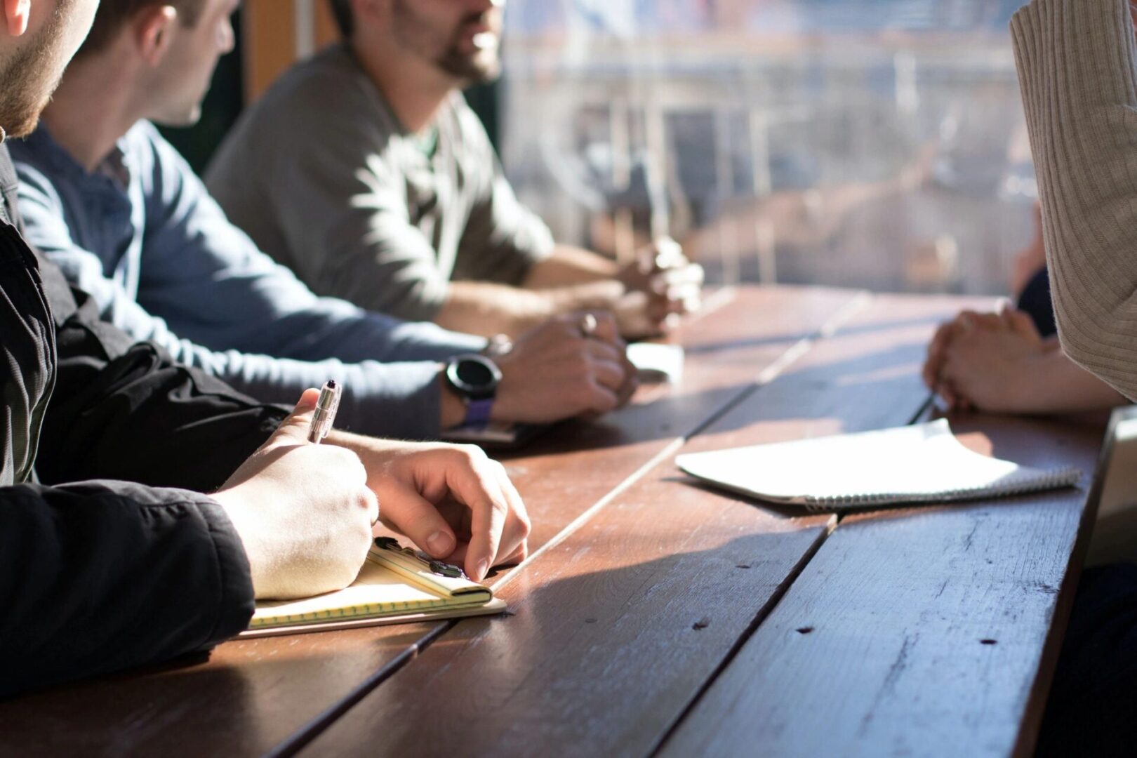 A group of people sitting at a table writing on paper.