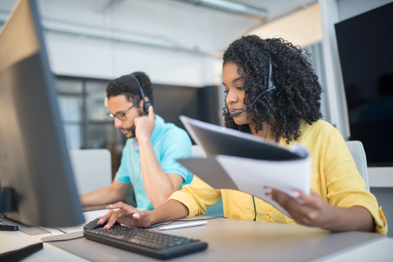 A man and woman sitting at a desk with computers.